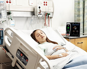 Patient sur un lit d'hôpital portant un capteur Masimo avec le dispositif Root à l'arrière-plan